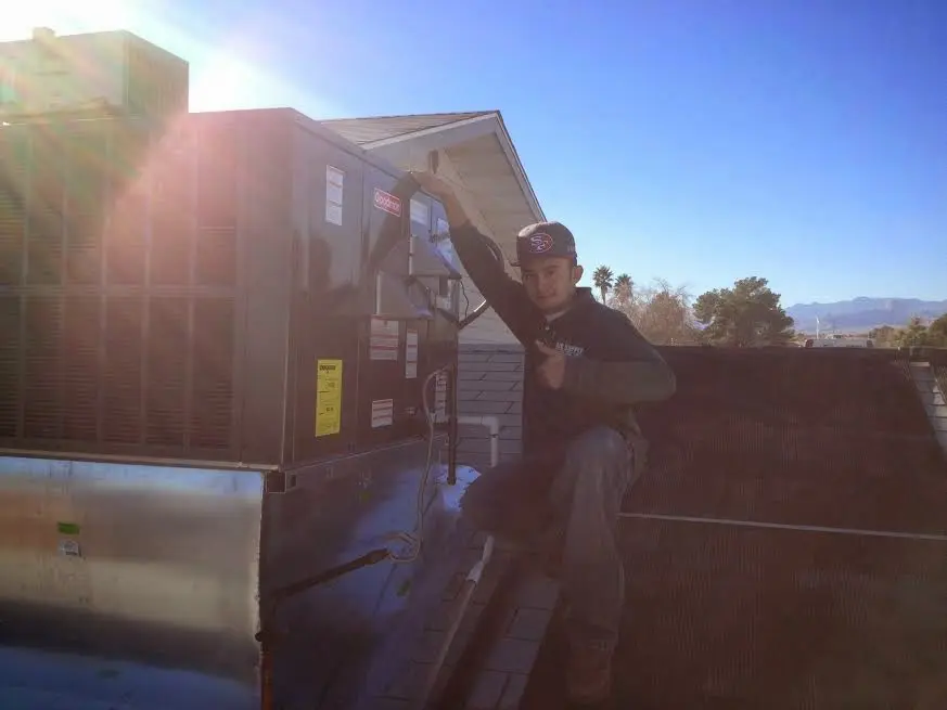 HVAC technician performing Air Duct Repair on a rooftop unit in University